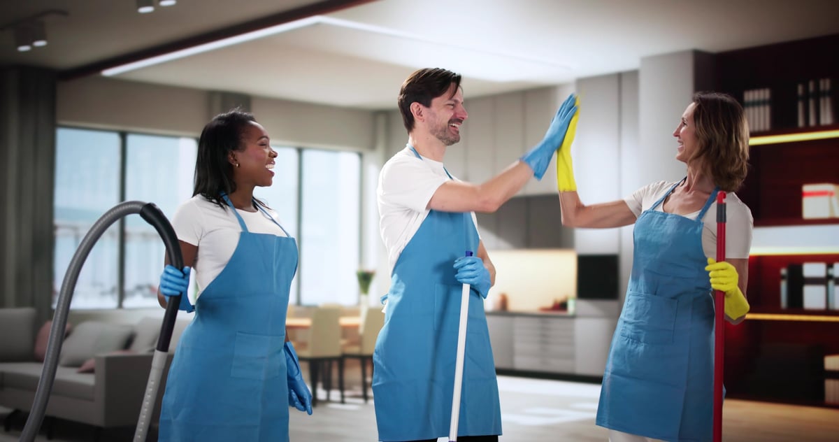Smiling janitor team giving high five in living room