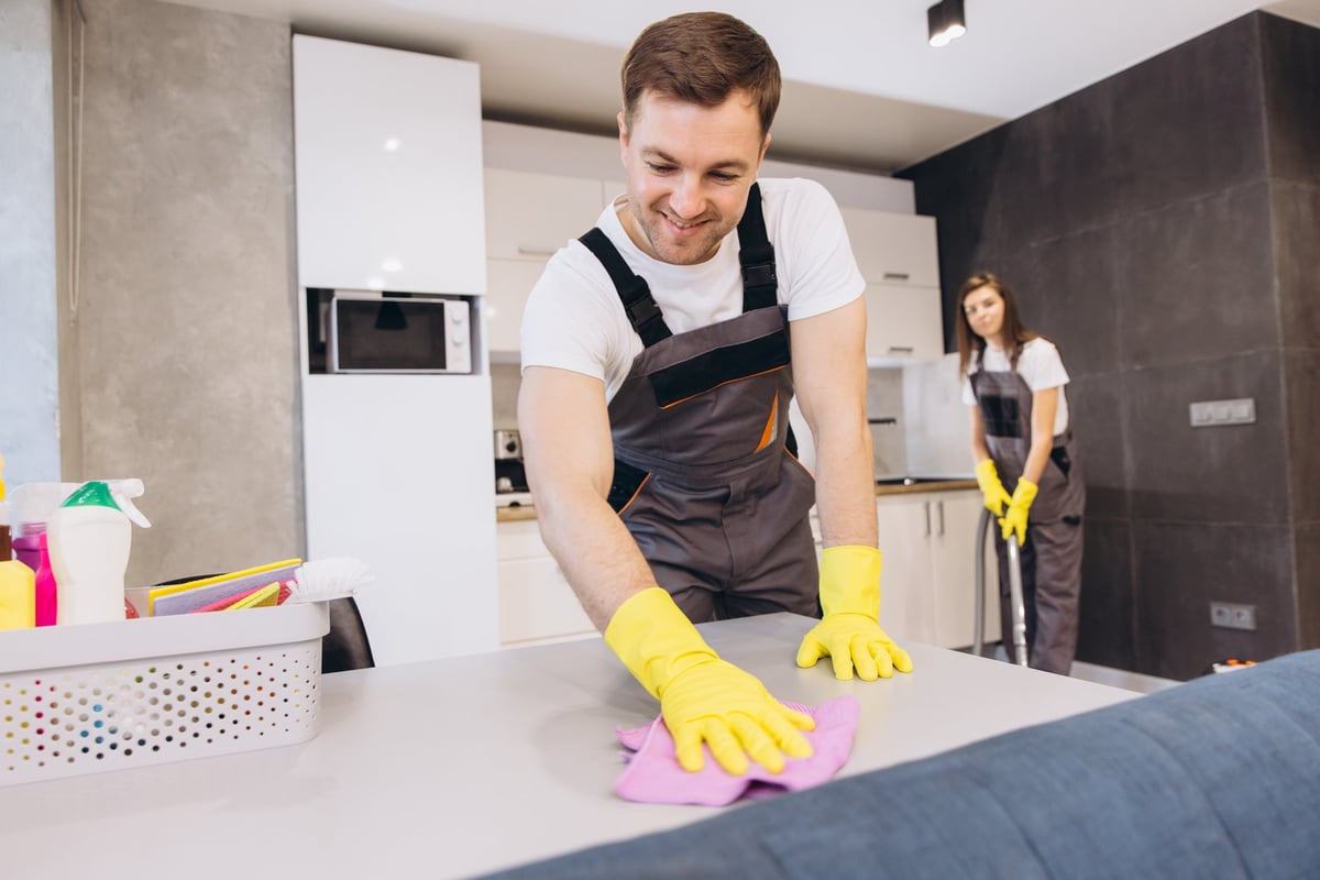 Cleaning company employees wearing uniforms cleaning a kitchen